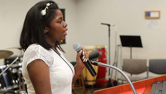 Photo of Sarina speaking into a microphone